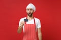 Shocked young bearded male chef cook or baker man in striped apron white t-shirt toque chefs hat isolated on red wall Royalty Free Stock Photo