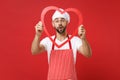 Shocked young bearded male chef cook or baker man in striped apron white t-shirt toque chefs hat isolated on red wall Royalty Free Stock Photo