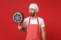 Shocked young bearded male chef cook or baker man in striped apron white t-shirt toque chefs hat posing isolated on red Royalty Free Stock Photo