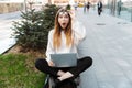 Shocked young business woman posing sitting outdoors near business center wearing eyeglasses using laptop computer Royalty Free Stock Photo