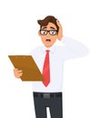 Shocked young businessman holding clipboard and keeping hand on head. Frustrated person carrying document, file or list.