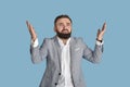 Shocked young businessman with raised hands in disbelief on blue studio background. Negative human emotions concept Royalty Free Stock Photo