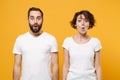 Shocked young couple friends bearded guy girl in white blank empty t-shirts posing isolated on yellow orange background Royalty Free Stock Photo