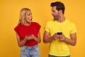 Shocked young couple friends in colored t-shirts isolated on yellow background. People lifestyle concept. Mock up copy space.