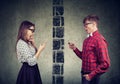 Shocked couple man and woman separated by wall texting each other on mobile phone