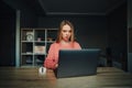 Shocked young freelancer woman sitting at home at the table and working on laptop, looking at the screen with a surprised face Royalty Free Stock Photo