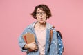 Shocked young girl student in denim clothes glasses backpack isolated on pastel pink background. Education in high Royalty Free Stock Photo