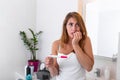 Shocked young girl with unwanted pregnancy looking the test in the bathroom. sad young woman holding pregnancy test feeling Royalty Free Stock Photo