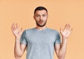 Shocked young man with arms up looking amazed in camera over yellow background