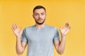 Shocked young man with arms up looking amazed in camera over yellow background
