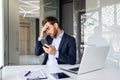 Shocked young man businessman sitting in the office on a chair and holding his head with his hand, holding the phone Royalty Free Stock Photo