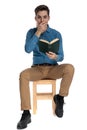 Shocked young man covering mouth with hand and holding book Royalty Free Stock Photo