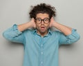 shocked young man with glasses covering ears, opening mouth and looking forward Royalty Free Stock Photo
