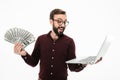 Shocked young man holding money and laptop computer. Royalty Free Stock Photo