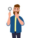 Shocked young man holding/showing magnifying glass and covering hand on mouth. Search, find, discovery, analyze, inspect. Royalty Free Stock Photo