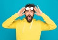 Shocked young man holding sunglasses above eyes and opening mouth