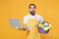 Shocked young man househusband in apron rubber gloves hold basin with detergent bottles washing cleansers doing Royalty Free Stock Photo