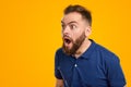 Shocked young man looking away with astonishment in yellow studio Royalty Free Stock Photo