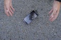 Shocked young man throws up her hands, her phone fell and crashed. Broken smartphone with cracked screen glass lays on