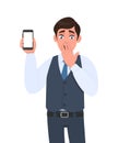 Shocked young man in vest suit showing mobile, cell or smartphone. Frustrated trendy person covering hand on mouth. Male character Royalty Free Stock Photo