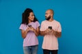 Shocked young man and woman using mobile phones together Royalty Free Stock Photo