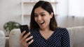 Young asian female looking at phone amazed with pleasant surprise Royalty Free Stock Photo