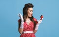 Shocked young pinup woman in retro dress holding landline phone receiver, feeling irritated about telephone conversation Royalty Free Stock Photo