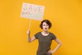Shocked young protesting woman hold protest sign broadsheet placard on stick isolated on yellow background studio