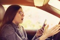 Shocked woman distracted by mobile phone texting while driving a car Royalty Free Stock Photo