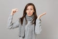 Shocked young woman in gray sweater, scarf spreading hands holding medication tablet, aspirin pill isolated on grey wall