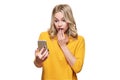 Shocked young woman holding up her mobile phone, reading shocking news. Woman in disbelief, isolated over white background.