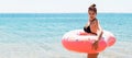 Shocked young woman inside donut rubber ring is standing in the cold water Royalty Free Stock Photo