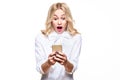 Shocked young woman looking at her mobile phone, screaming in disbelief. Woman staring at shocking text message on her phone. Royalty Free Stock Photo