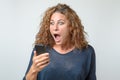 Shocked young woman staring at her mobile Royalty Free Stock Photo