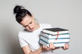 Shocked, young woman student with glasses on head holds a stack of books in her hands and looks at them puzzled, on a white Royalty Free Stock Photo