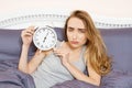 Shocked young woman waking up with alarm, overslept work, bad sleep insomnia. Girl hold clock when lying on bed in the morning Royalty Free Stock Photo