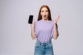 Shocked young woman wearing stylish casual clothes holding cell phone with black empty mobile screen Royalty Free Stock Photo