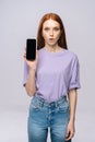 Shocked young woman wearing stylish clothes holding cell phone with black empty mobile screen Royalty Free Stock Photo