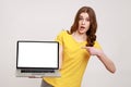 Shocking advertising. Portrait of amazed teenager girl in casual yellow T-shirt pointing at laptop Royalty Free Stock Photo