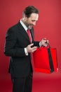 Shocking discount. Mature businessman hold paper bag gift red background. Shopping concept. Christmas gift. Happy