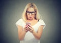 Shocking message. Surprised blond hair woman holding mobile phone and staring at it Royalty Free Stock Photo