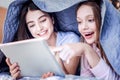 Positive two girls laughing at film under blanket