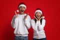 Shocking Offer. Surprised Couple Wearing Santa Hats Spreading Hands, Exclaiming With Excitement