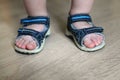 Shod legs of the baby. Children`s sandals on their feet. Toddler shoes. Tourist sandals for the smallest travelers. A new purchase Royalty Free Stock Photo