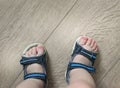 Shod legs of the baby. Children`s sandals on their feet. Toddler shoes. Tourist sandals for the smallest travelers. A new purchase Royalty Free Stock Photo