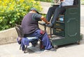 Bootblack Man working on the street polishing the shoes of businessman reading daily newspaper. Lima, Peru. Royalty Free Stock Photo