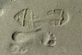 Shoe print and footprint on wet sand Royalty Free Stock Photo