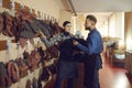 Male and female shoemaker colleague discussing shoes material choice on stand