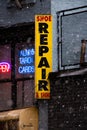 Shoe repair sign outside of storefront in city environment during snow storm Royalty Free Stock Photo