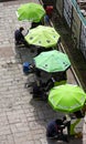 Shoe shiners under green umbrellas